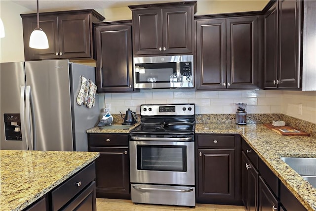 kitchen with light stone countertops, stainless steel appliances, decorative light fixtures, decorative backsplash, and dark brown cabinets