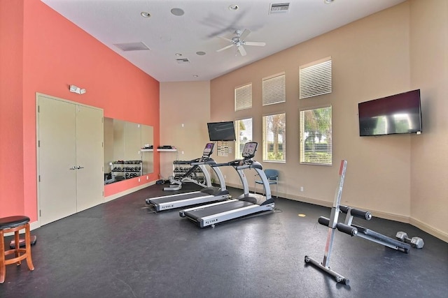 exercise room featuring ceiling fan and a high ceiling