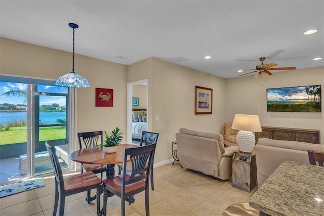 tiled dining area featuring a water view and ceiling fan