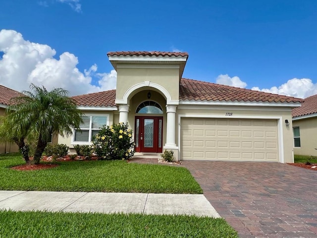 mediterranean / spanish home featuring a garage and a front lawn