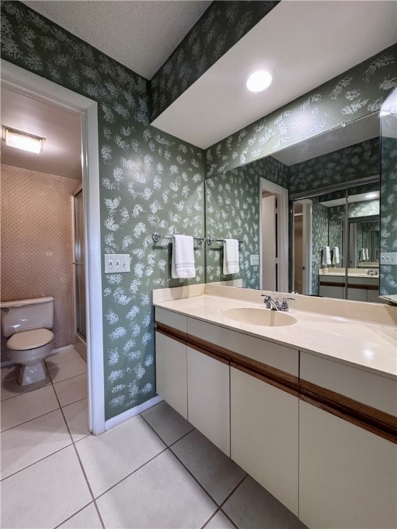 bathroom featuring tile patterned flooring, vanity, an enclosed shower, and toilet