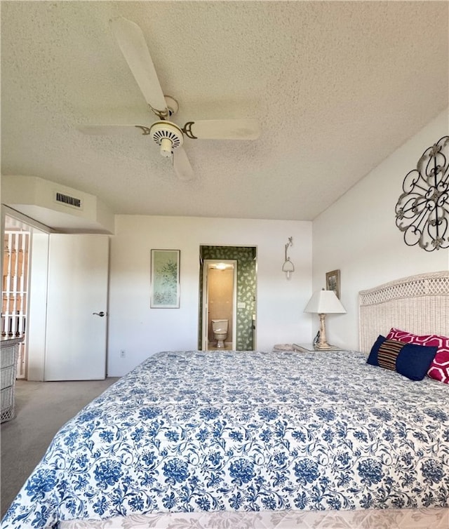 bedroom featuring carpet flooring, ceiling fan, ensuite bathroom, and a textured ceiling