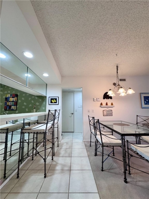 tiled dining space featuring a notable chandelier and a textured ceiling