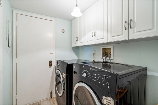 laundry room with cabinets, light wood-type flooring, and washer and clothes dryer