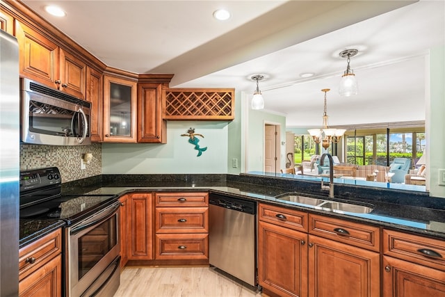 kitchen featuring dark stone countertops, decorative light fixtures, appliances with stainless steel finishes, and sink