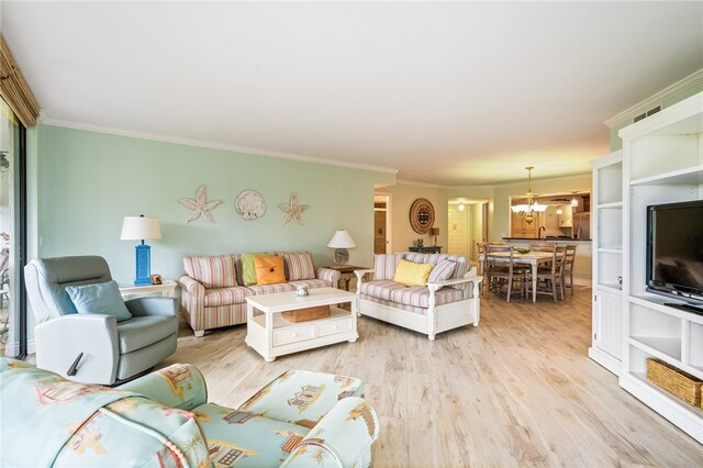 living room with light wood-type flooring, a notable chandelier, and crown molding