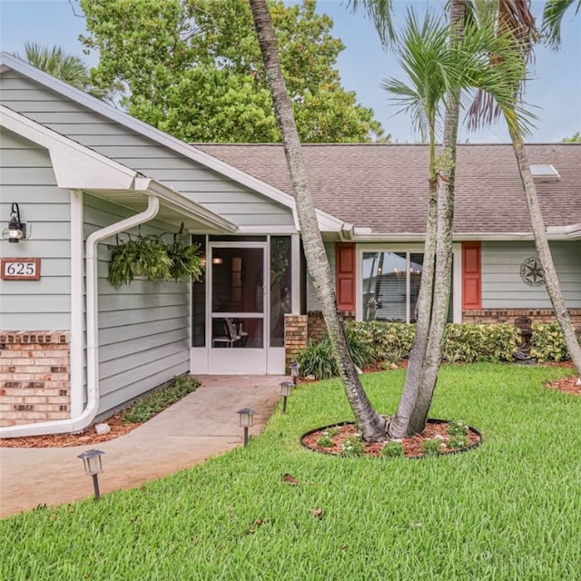 view of front of house featuring a sunroom and a front yard