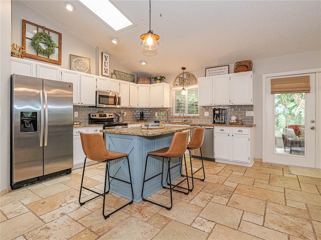 kitchen with stainless steel appliances, white cabinetry, hanging light fixtures, and a breakfast bar area