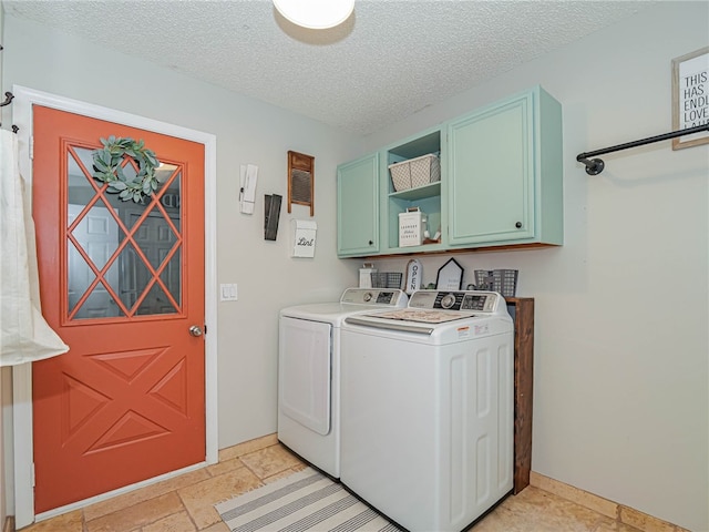 clothes washing area with cabinets, a textured ceiling, and washing machine and clothes dryer