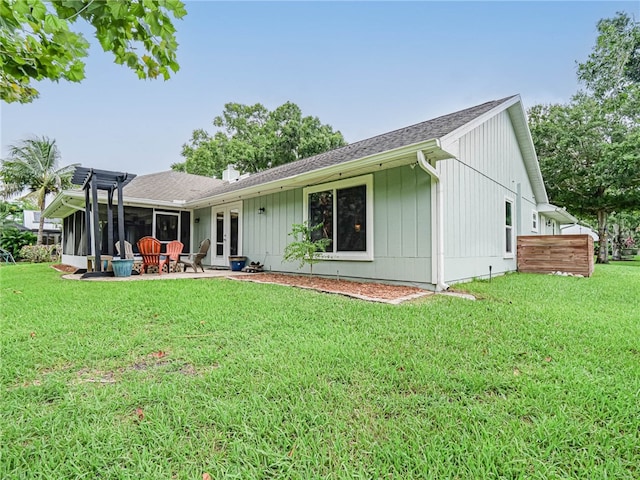 rear view of property featuring a lawn, a patio area, and a sunroom