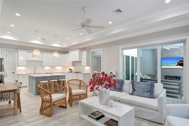 1618 W Sandpointe Pl, Vero Beach, FL 32963 - living area with a ceiling fan, crown molding, light wood-style floors, a tray ceiling, and recessed lighting