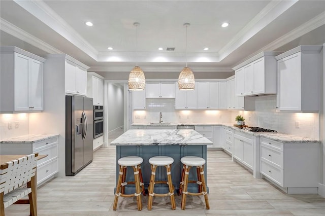 1618 W Sandpointe Pl, Vero Beach, FL 32963 - kitchen featuring appliances with stainless steel finishes, a tray ceiling, a kitchen island, white cabinetry, and tasteful backsplash