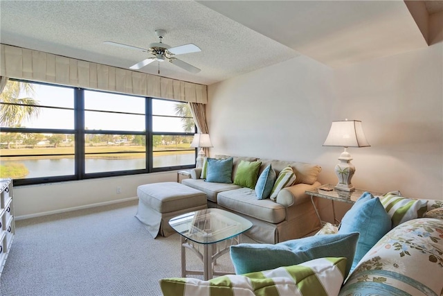 carpeted living room with baseboards, a textured ceiling, a ceiling fan, and a water view