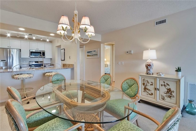 dining room featuring visible vents, a textured ceiling, a chandelier, and carpet