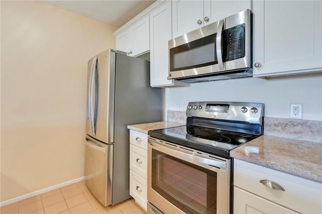 kitchen with light stone counters, white cabinetry, appliances with stainless steel finishes, light tile patterned floors, and baseboards