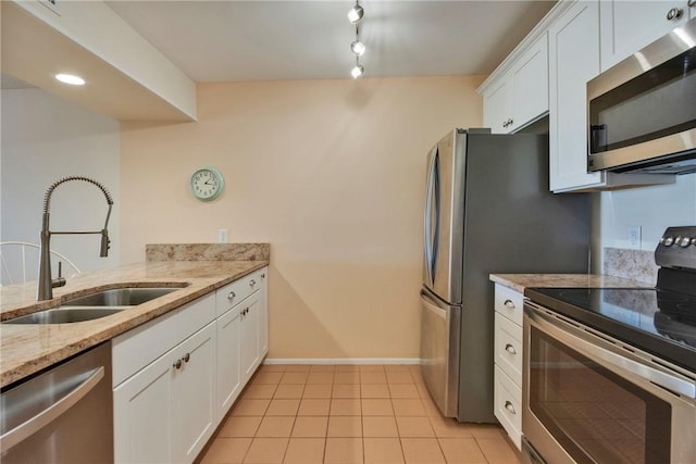 kitchen featuring white cabinetry, light stone countertops, appliances with stainless steel finishes, and a sink