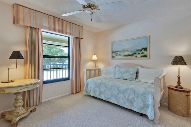 bedroom featuring baseboards, carpet floors, a textured ceiling, and ceiling fan