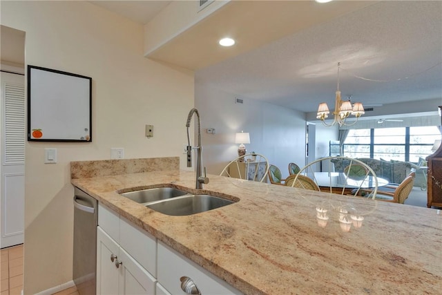 kitchen with a sink, stainless steel dishwasher, white cabinets, light stone countertops, and hanging light fixtures