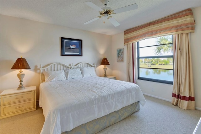 bedroom with baseboards, light colored carpet, ceiling fan, and a textured ceiling