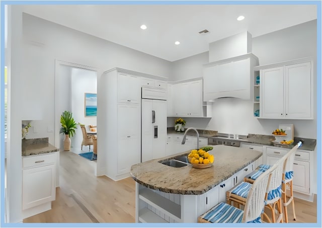 kitchen featuring sink, light hardwood / wood-style flooring, white cabinetry, and paneled built in fridge