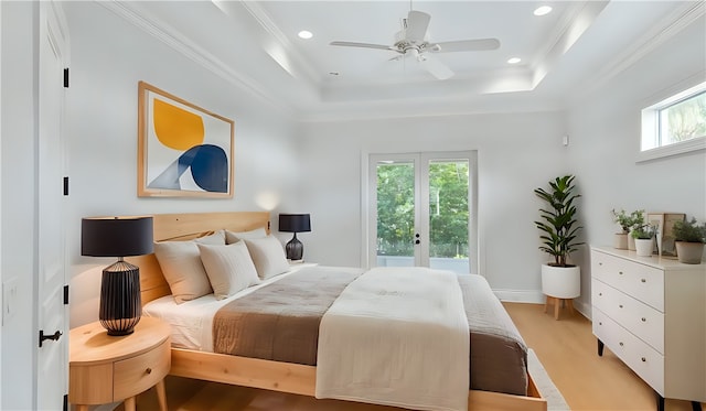 bedroom with a raised ceiling, light hardwood / wood-style flooring, multiple windows, and ceiling fan