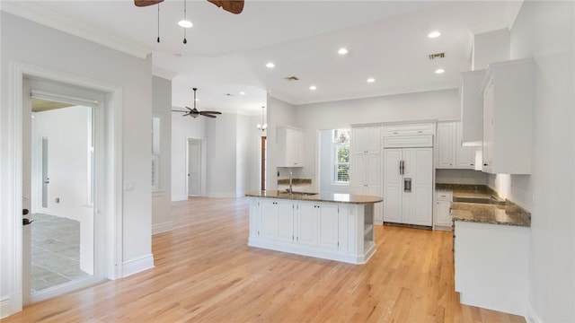 kitchen with white cabinets, light wood-type flooring, ceiling fan, and paneled built in fridge