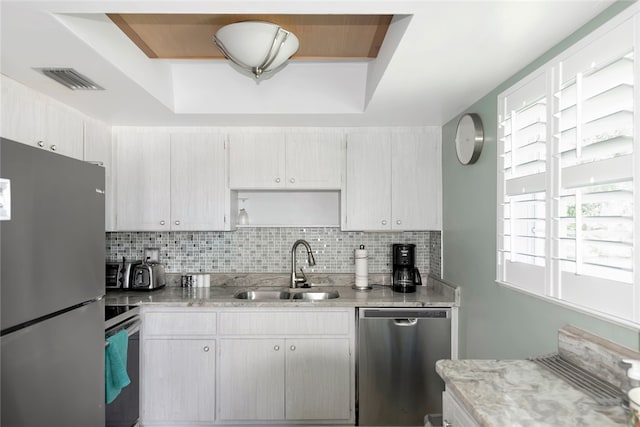 kitchen with stainless steel appliances, sink, a raised ceiling, and backsplash