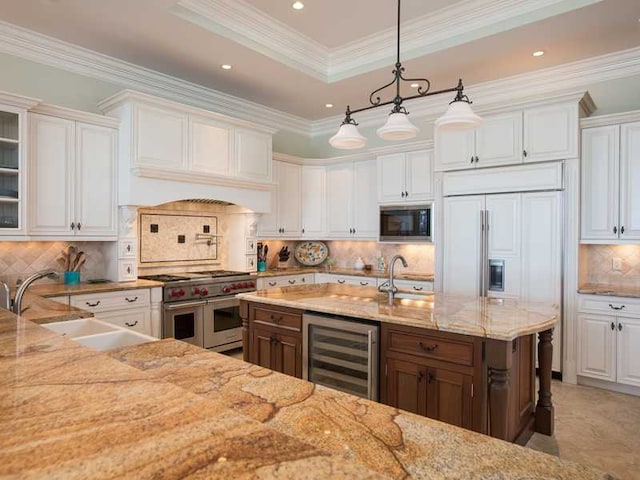 kitchen featuring sink, white cabinetry, built in appliances, decorative light fixtures, and beverage cooler