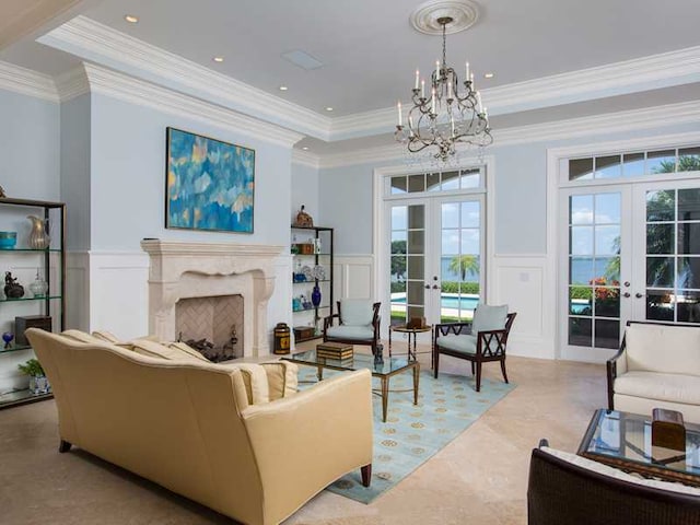 living room with french doors, a tray ceiling, a premium fireplace, and a chandelier