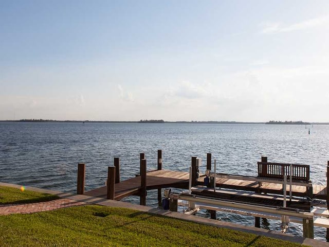 dock area with a lawn and a water view