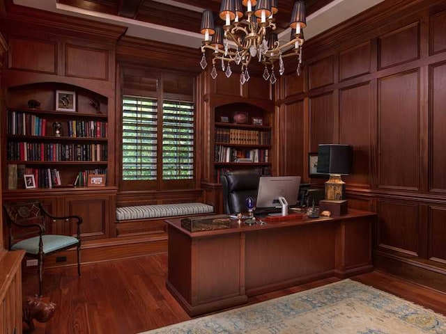 home office featuring wood walls, an inviting chandelier, crown molding, dark hardwood / wood-style flooring, and built in features