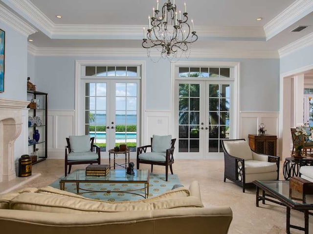 interior space with french doors, a tray ceiling, a chandelier, and crown molding