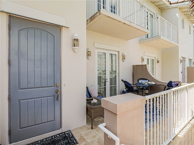 view of exterior entry featuring french doors and a balcony