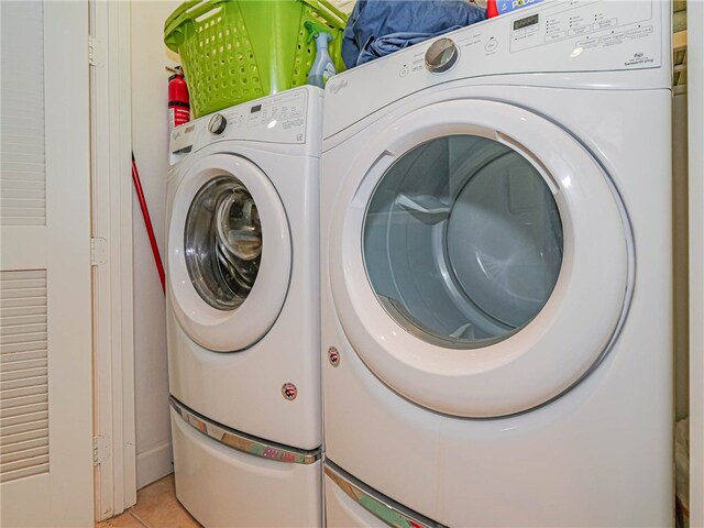 clothes washing area with independent washer and dryer and light tile patterned floors