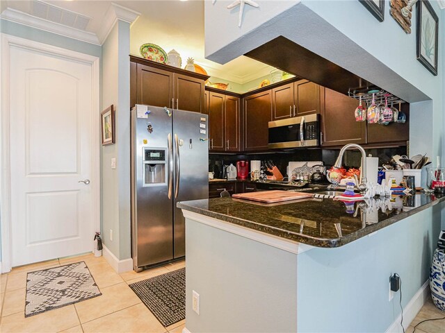 kitchen featuring dark stone countertops, kitchen peninsula, appliances with stainless steel finishes, and dark brown cabinetry