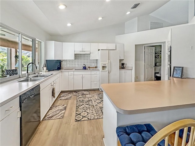 kitchen featuring white fridge with ice dispenser, dishwasher, lofted ceiling, and a sink