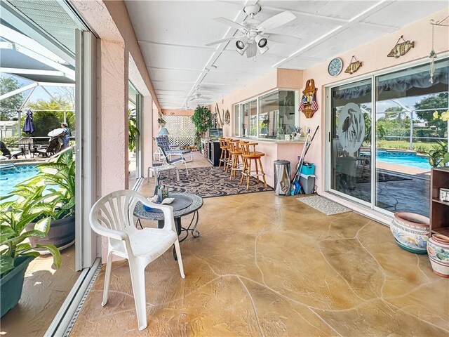 sunroom featuring a wealth of natural light, ceiling fan, and outdoor dry bar
