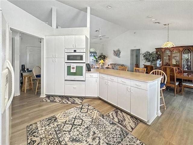 5207 Indian Bend Ln, Fort Pierce, FL 34951 - kitchen featuring a kitchen bar, light wood finished floors, vaulted ceiling, a peninsula, and a ceiling fan