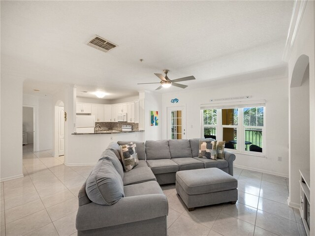 living room with ornamental molding, ceiling fan, and light tile patterned flooring