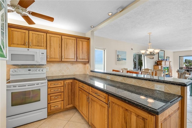 kitchen featuring kitchen peninsula, light tile patterned floors, a chandelier, and white appliances