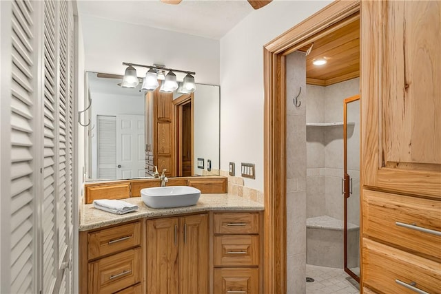 bathroom with a tile shower and vanity