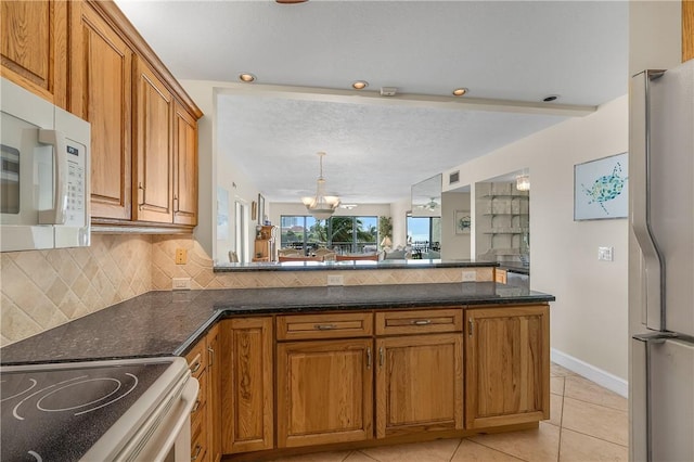 kitchen featuring tasteful backsplash, stainless steel fridge, a chandelier, light tile patterned flooring, and range