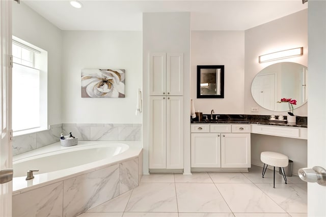 bathroom featuring vanity, a healthy amount of sunlight, and tiled tub