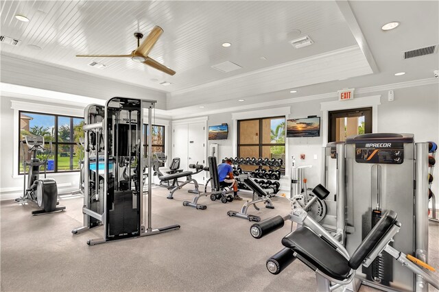 gym with crown molding, ceiling fan, and a tray ceiling