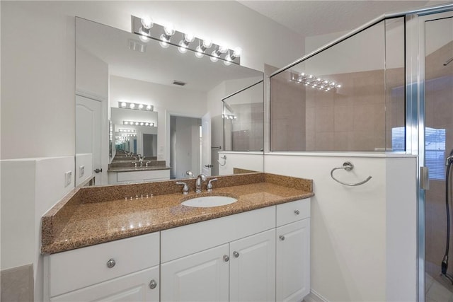 bathroom with a textured ceiling, vanity, and walk in shower