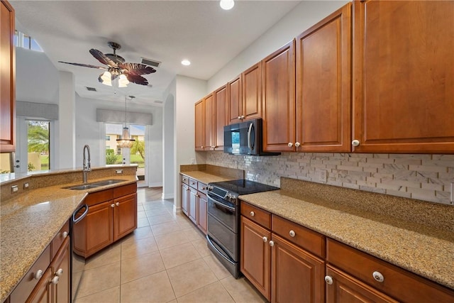 kitchen with light stone countertops, tasteful backsplash, sink, black appliances, and light tile patterned floors