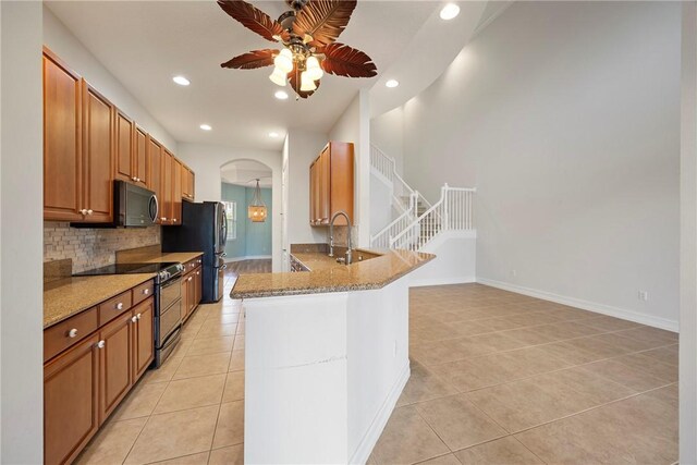 kitchen featuring light stone countertops, black range with electric cooktop, kitchen peninsula, decorative backsplash, and light tile patterned floors