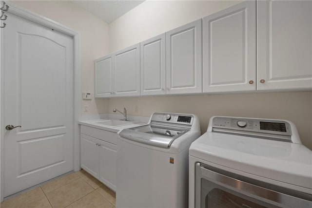 clothes washing area with light tile patterned flooring, cabinets, sink, and washing machine and clothes dryer