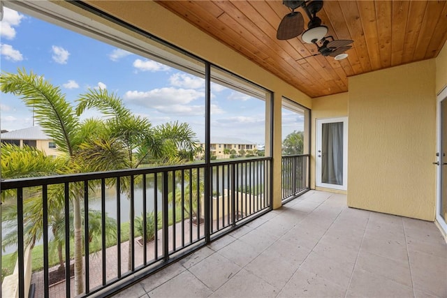 unfurnished sunroom with ceiling fan, a water view, and wood ceiling