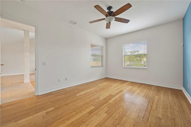 empty room with a textured ceiling, light hardwood / wood-style floors, and ceiling fan